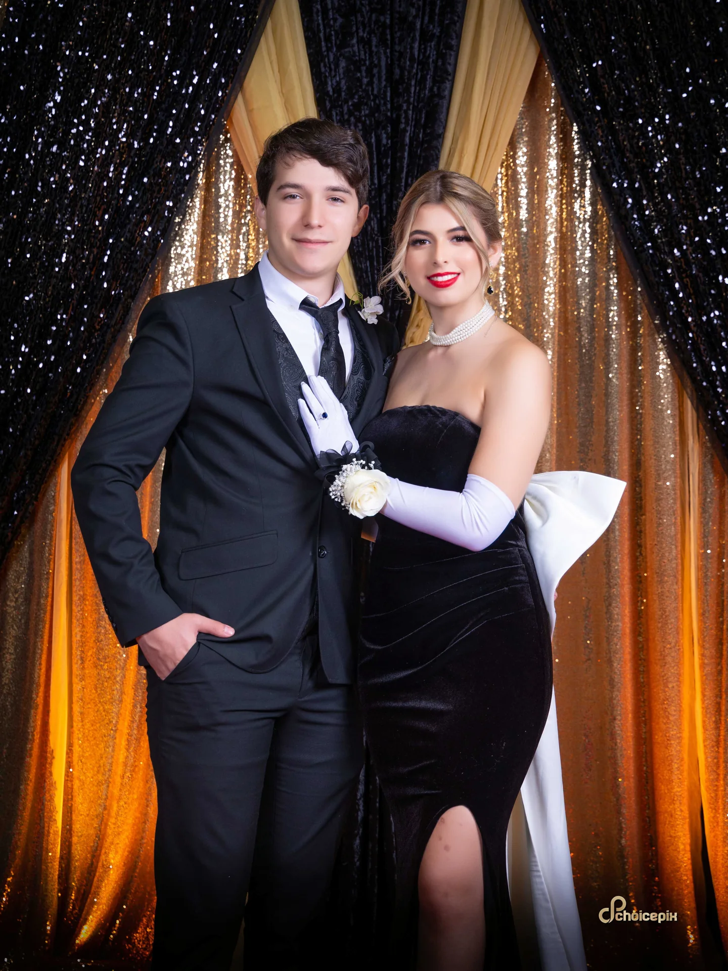 Prom couple in a black tuxedo and a black gown with white gloves